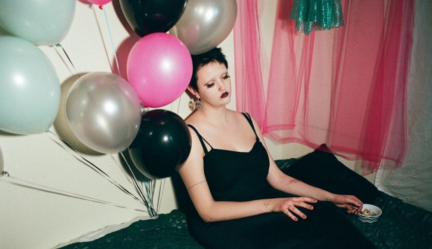 A woman sitting on a bed with balloons.