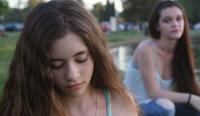 Two girls sitting next to each other in a park.