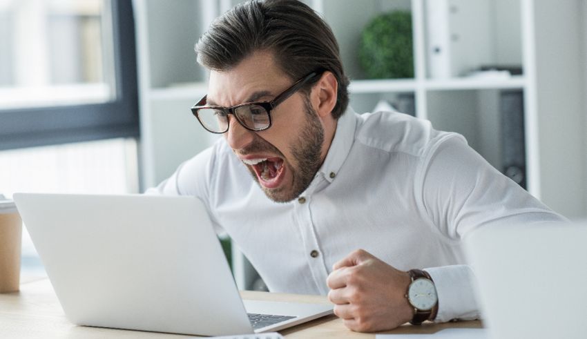 A man yelling at his laptop in the office.