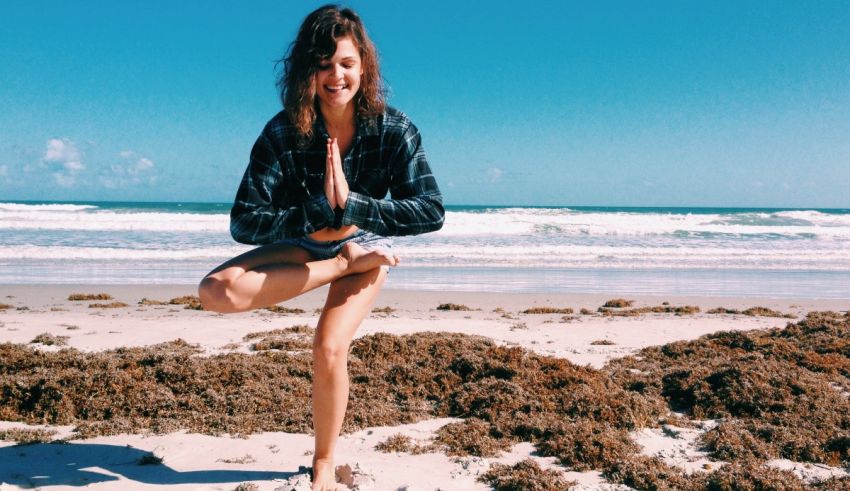 A woman doing yoga on the beach.