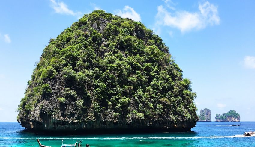 A group of people on a boat in front of a large rock.