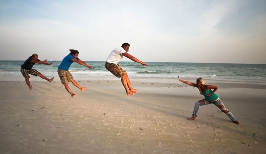 A group of people jumping in the air on the beach.