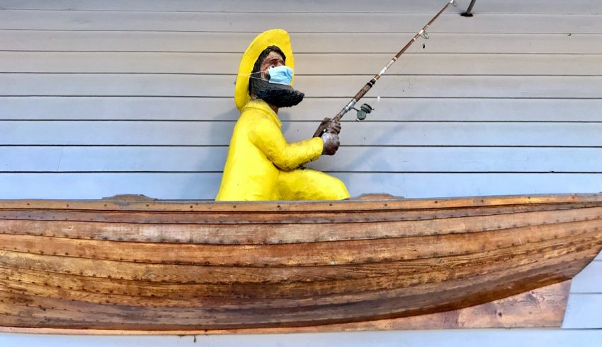 A wooden statue of a man fishing in a boat.