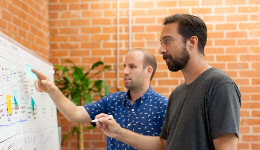 Two men standing in front of a whiteboard.