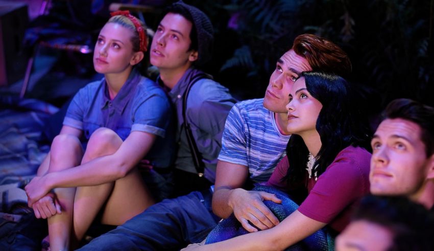A group of people sitting on the ground watching a movie.