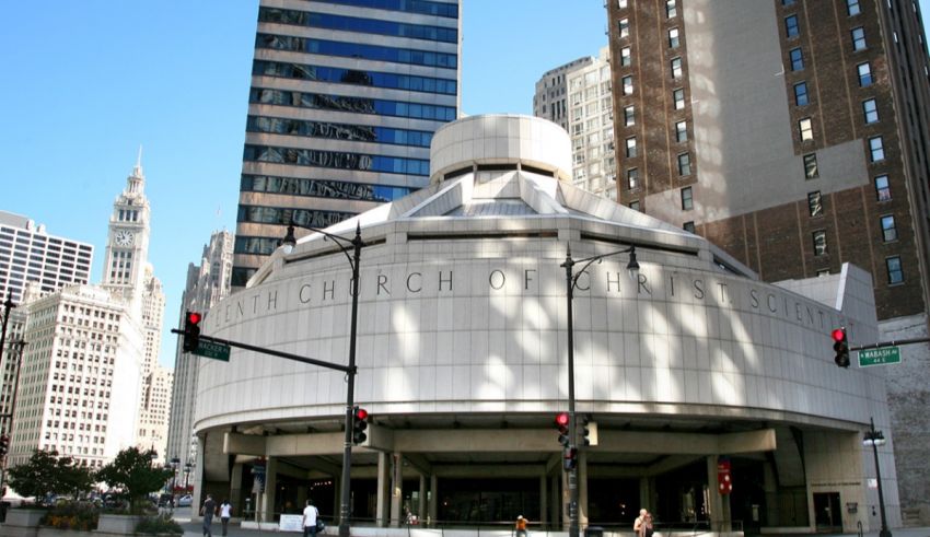 A white building with a circular roof in the middle of a city.