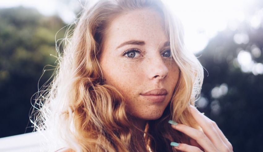 A young woman with freckles is posing for a photo.