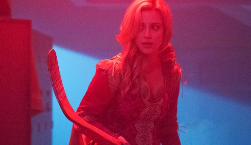 A woman holding a hockey stick in a dark room.