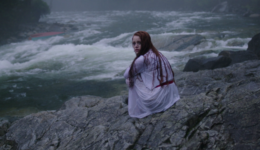 A woman sitting on rocks near a river.