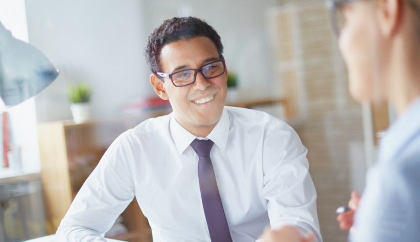 A man and woman talking at a desk in an office.