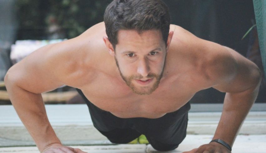 A man doing push ups on a concrete floor.