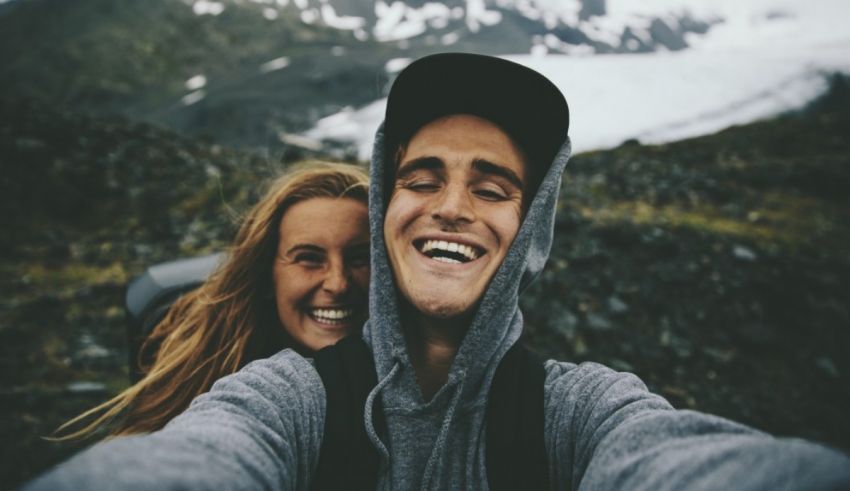 A man and woman taking a selfie in front of a mountain.