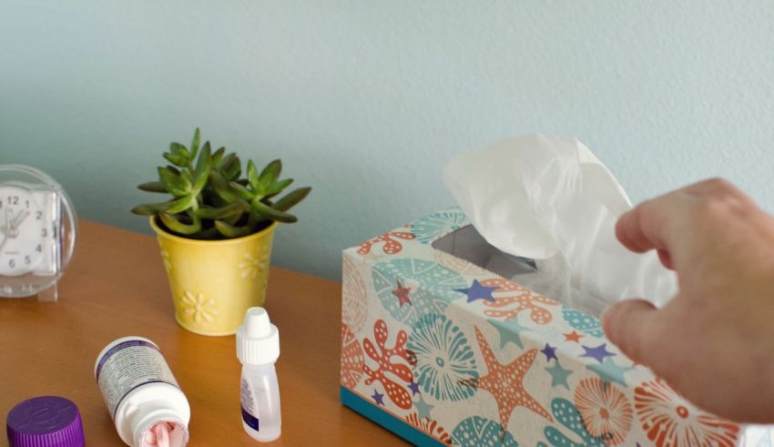 A hand reaching for a tissue box on a table.