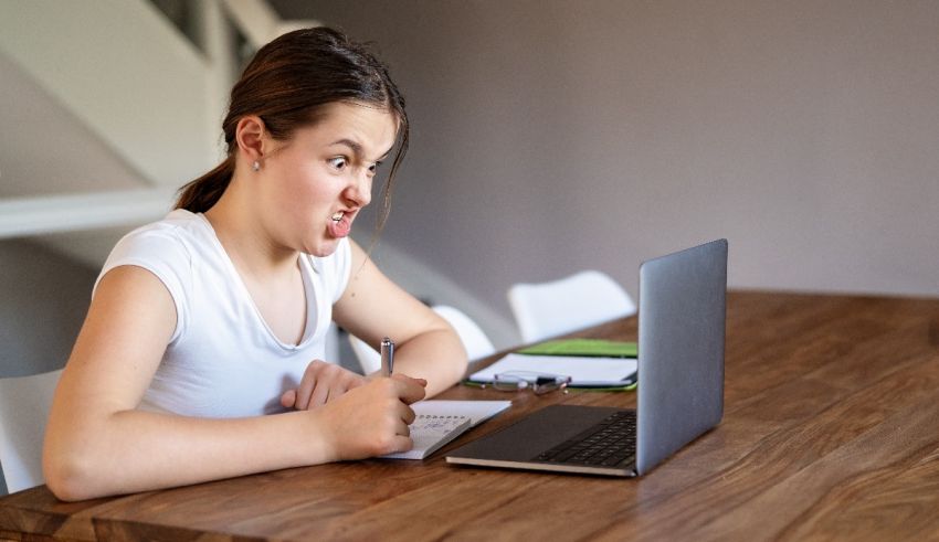 A girl sitting at a table with a laptop.
