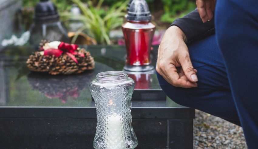 A man is laying a candle on a grave.