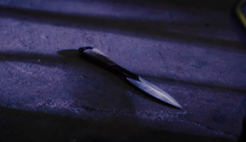 A knife laying on a concrete floor.