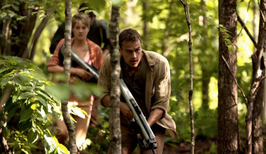 A man and woman walking through the woods with rifles.