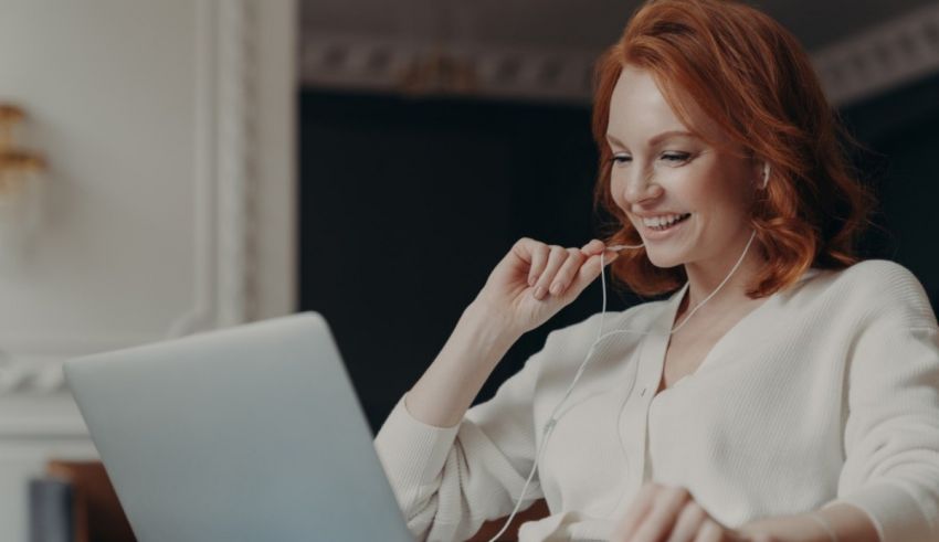 A woman is using a laptop while listening to music.