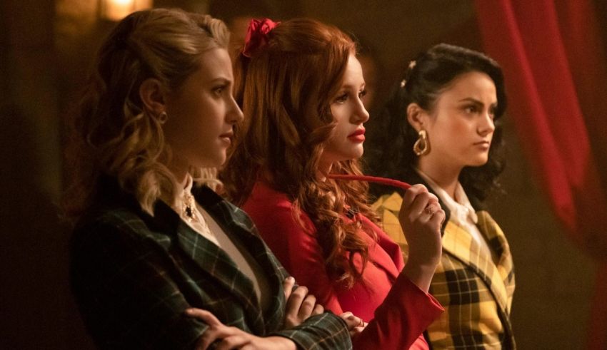 A group of women dressed in plaid are standing in front of a curtain.