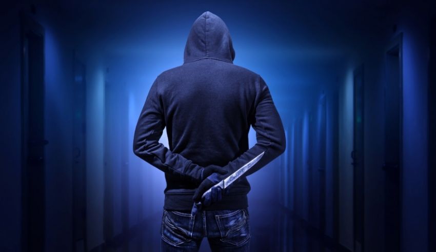 A man in a hoodie is standing in a dark hallway.
