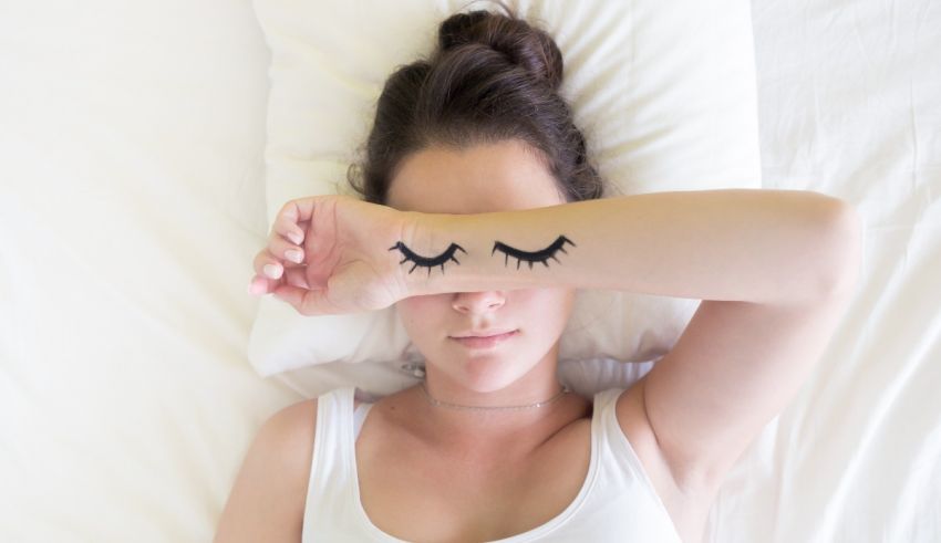 A woman laying on her bed with eyelashes painted on her face.
