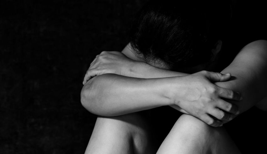 A black and white photo of a woman with her hands on her knees.