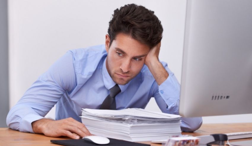 A man sitting at his desk with a pile of papers on his head.