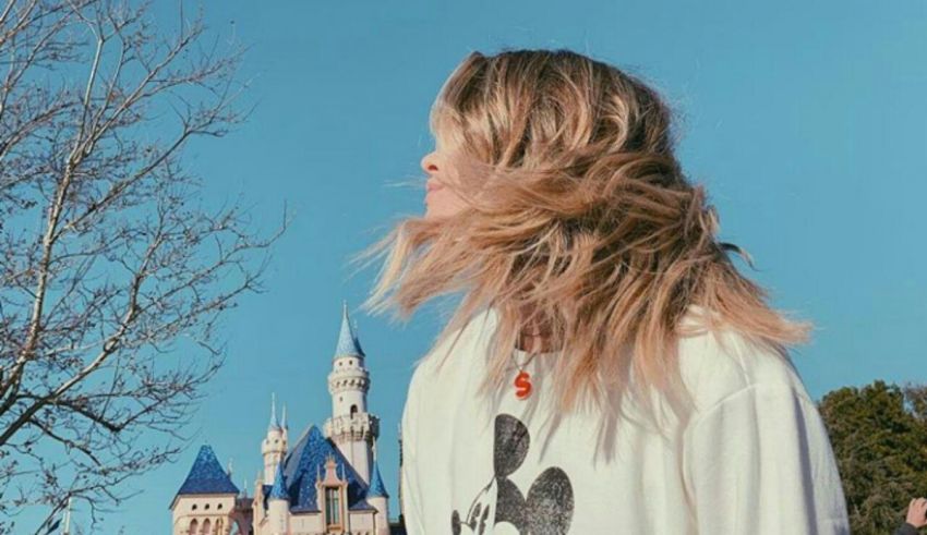 A woman is standing in front of a castle at disneyland.