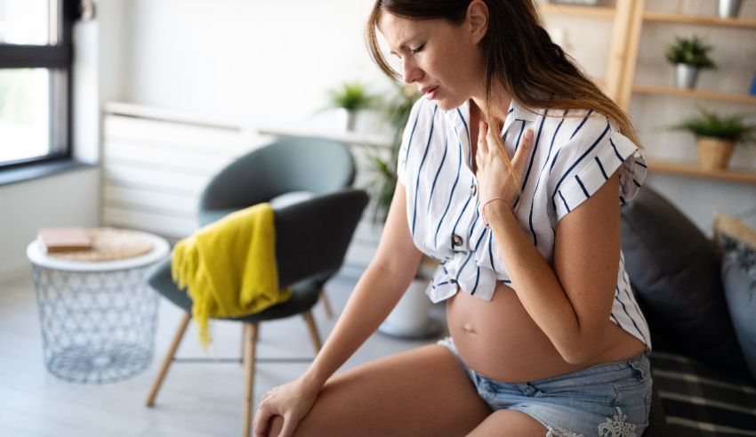 A pregnant woman is sitting on a couch in a living room.