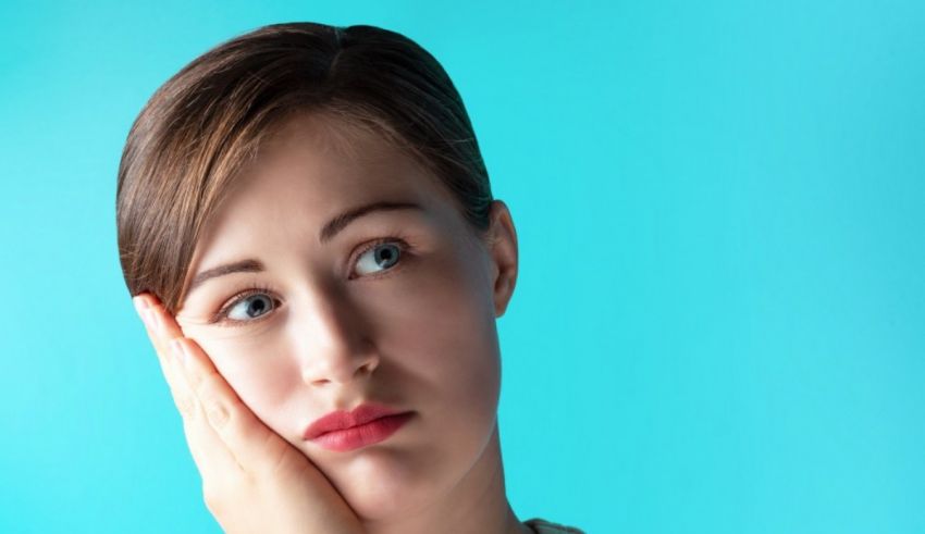 A woman with a toothache is holding her hand in front of her face.