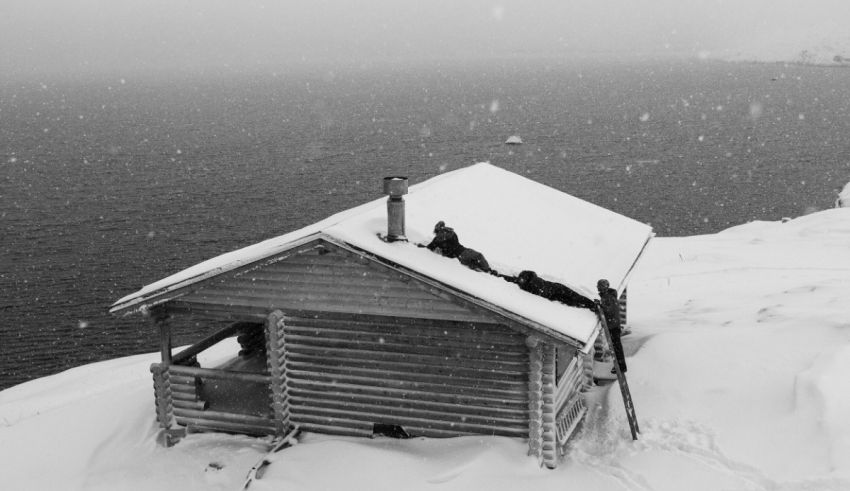 A black and white photo of a cabin on top of a cliff.