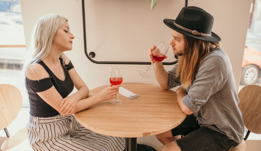 A man and woman sitting at a table drinking wine.