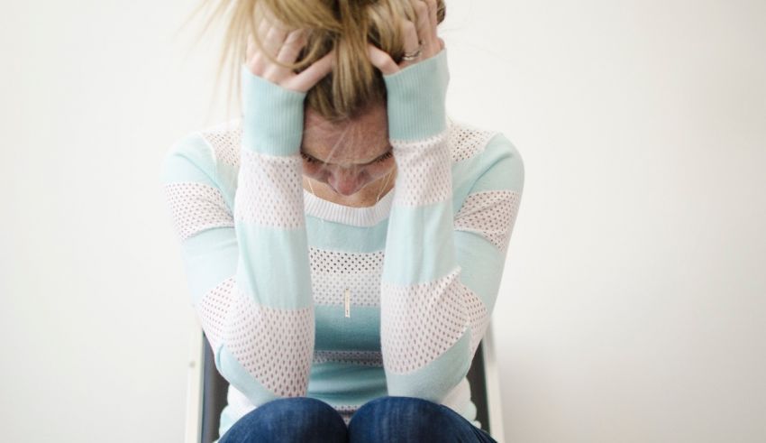 A woman sitting on a chair with her hands on her head.
