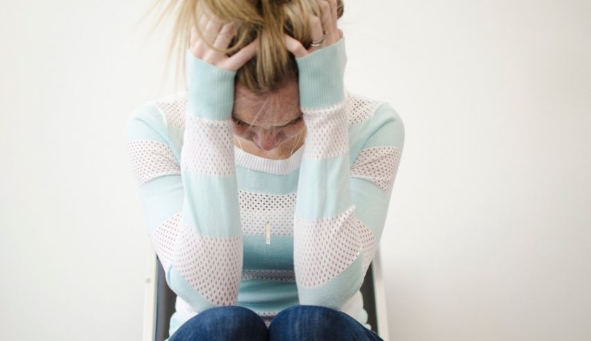 A woman sitting on a chair with her hands on her head.