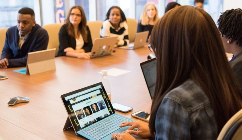 A group of people sitting around a conference table with laptops.