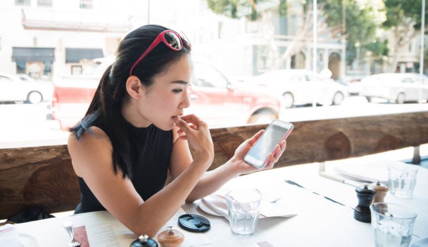 A woman sitting at a table looking at her phone.