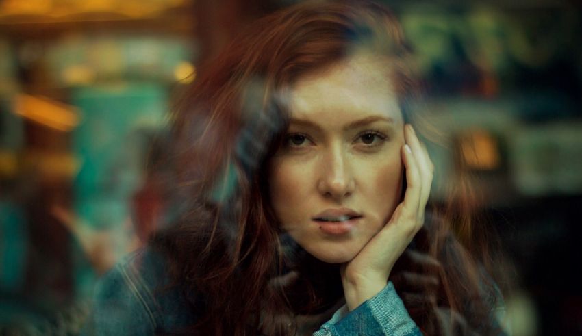 A woman with red hair looking out of a window.