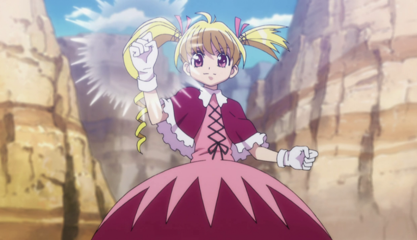 A girl in a pink dress standing in a rocky area.