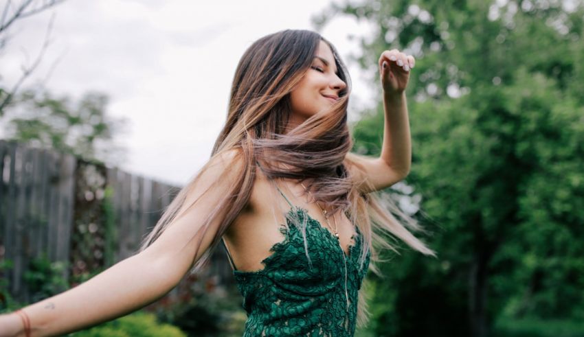 A woman in a green dress with her hair in the air.