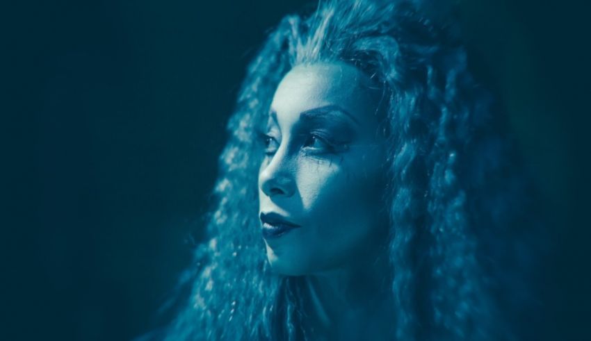 A woman with long curly hair in a blue dress.