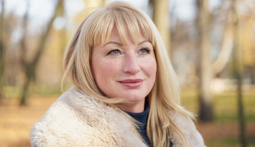 A woman in a fur coat standing in a park.