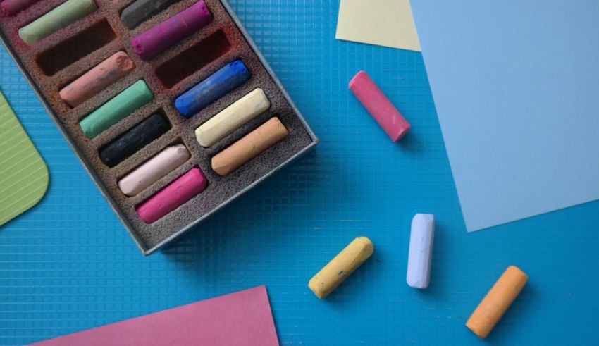 A box of colored crayons on a blue table.