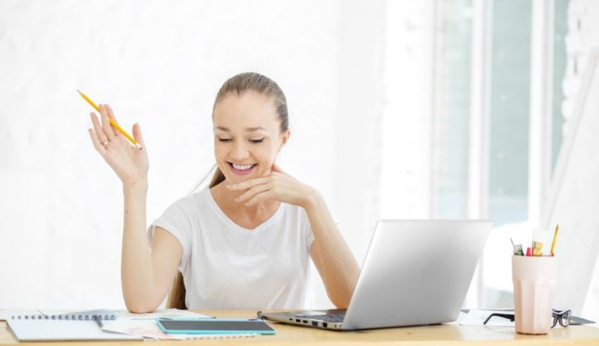 A young woman sitting at a desk with a laptop and a pencil.