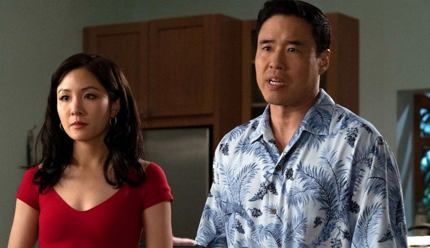 A man and woman in a hawaiian shirt standing in a kitchen.