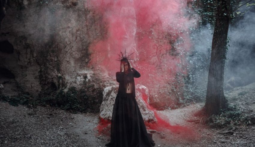 A woman in a red dress standing in a forest.