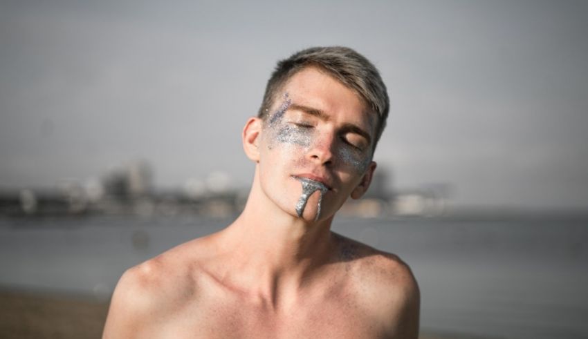 A man with silver paint on his face on the beach.