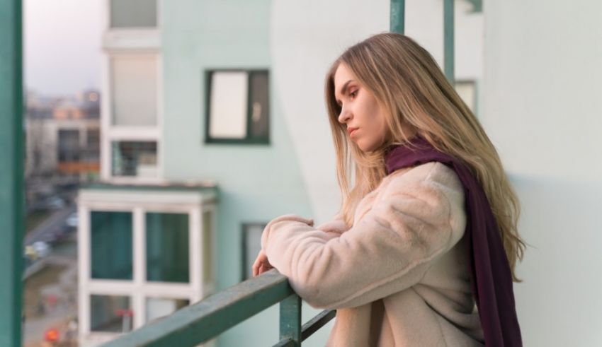 A woman is sitting on a balcony looking out at the city.