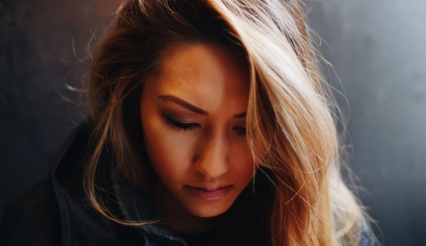 A woman with long hair looking down at her phone.