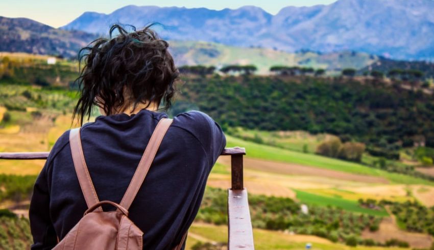 A woman with a backpack looking out over a valley.