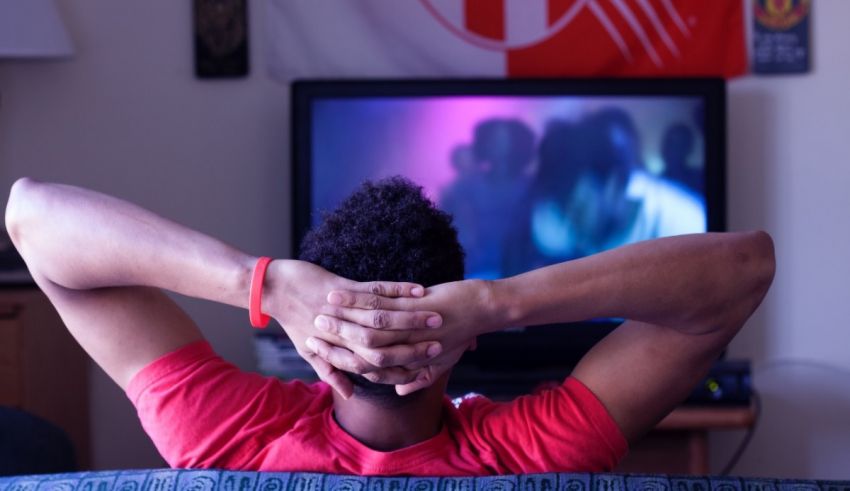 A man is sitting on a couch watching tv.